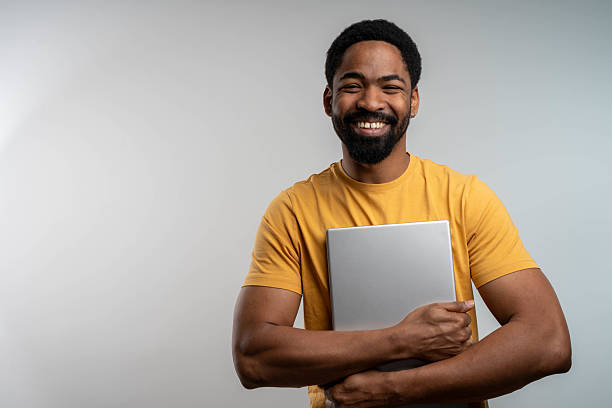 istock Smiling young man holding closed laptop 2232717491