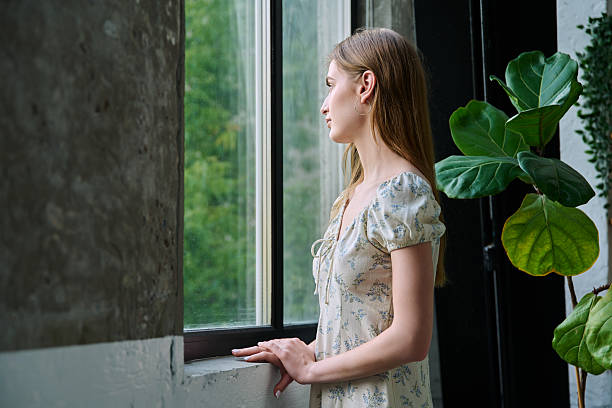 istock Young beautiful dreaming romantic girl looking out the window 2232722006