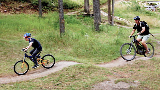 Father and son ride mountain bicycles on pathway in forest, Canadian Rockies, Alberta
