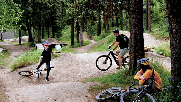 Father and sons ride mountain bicycles on pathway in forest