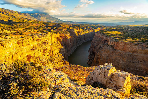 A breathtaking scenic view of a golden sunset from Devil's Canyon Overlook, casting a warm glow over the dramatic landscape of Bighorn Canyon