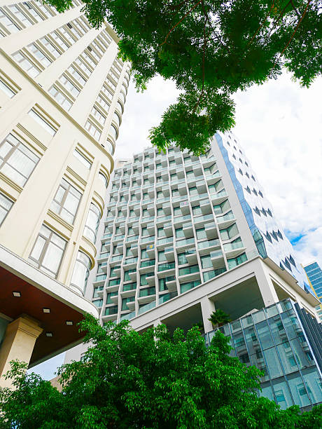 istock Low-angle view of contrasting buildings in Danang, one with classical beige facade and ornate windows, the other with sleek glass exterior. Overcast sky highlights architectural evolution 2232734603