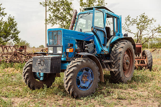 blue tractor with trailer stands in agricultural area on sunny summer day