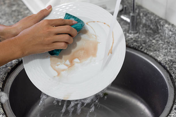 istock A woman washing a dish with a sponge 2232736096