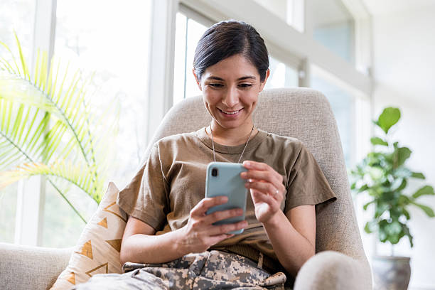 istock Smiling Woman in Military Uniform Using Smart Phone 2232737889