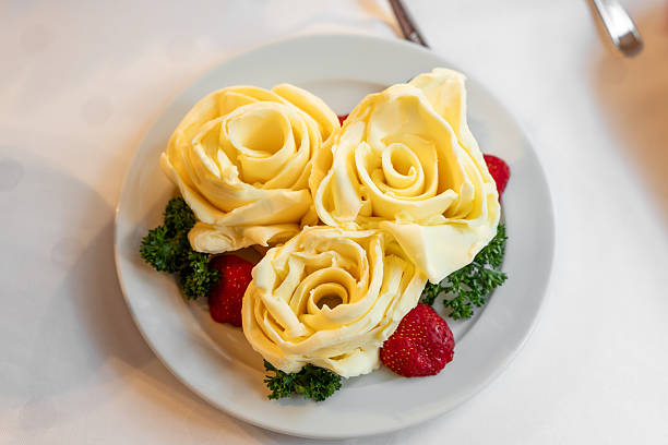Butter rose flowers at a buffet. Food as decoration in a blossom shape. Diary product for lunch or dinner in a restaurant. Professional catering at an event.