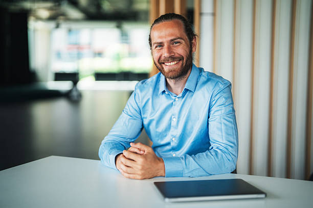 istock Thoughtful business man sitting on a desk and smiling 2232750572
