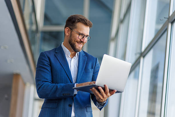 istock Smiling businessman working on laptop in modern office 2232751784