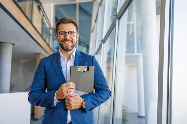 istock Smiling businessman holding clipboard in modern office building 2232751829