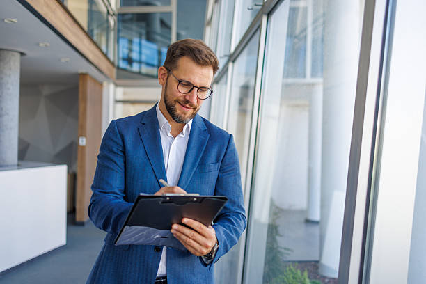 istock Businessman writing notes on clipboard in modern office 2232751848