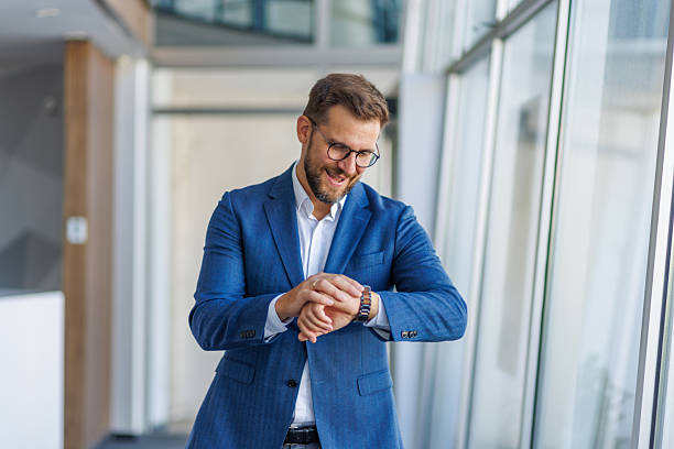 istock Businessman checking time on wristwatch in office corridor 2232752020