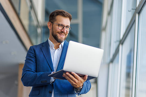 istock Smiling businessman using laptop in modern office 2232752030