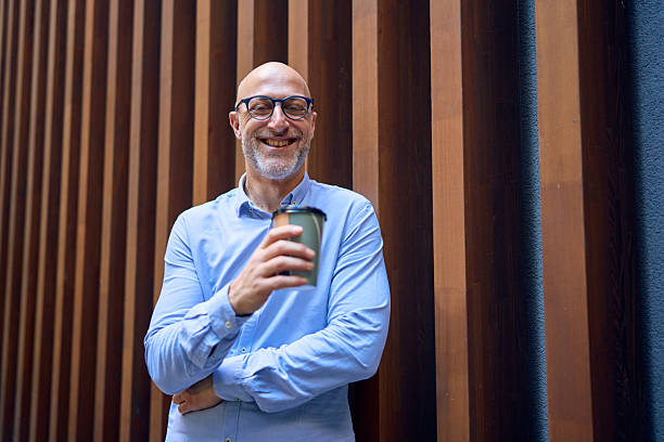 istock Smiling businessman drinking coffee during a work break 2232754416