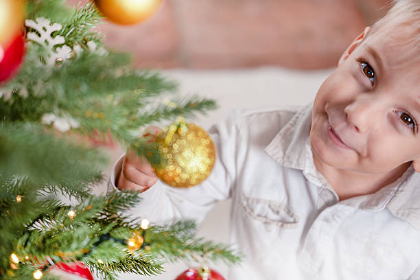 istock Smiling Child Decorating Christmas Tree with Golden Ornament 2232759814