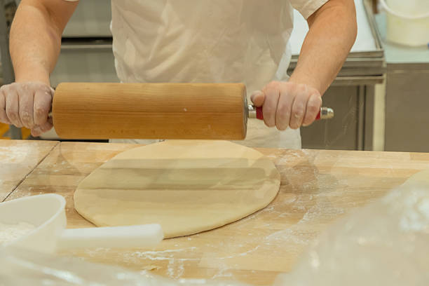 istock Baker rolling dough on wooden surface with flour and kitchen tools in a professional setting 2232761292