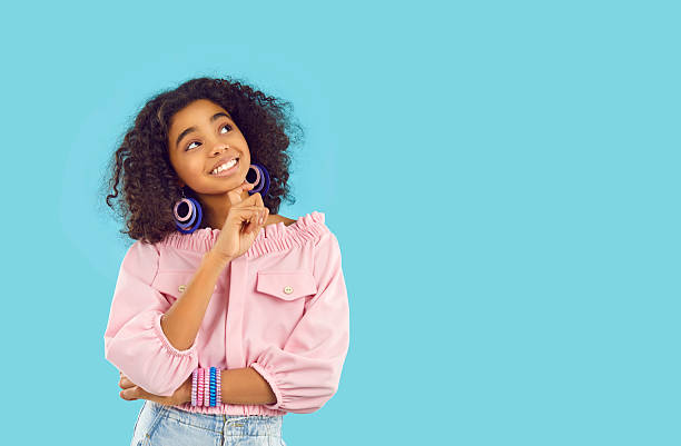 istock Happy child on blue copy space background thinking of something good, looking up and smiling 2232765721