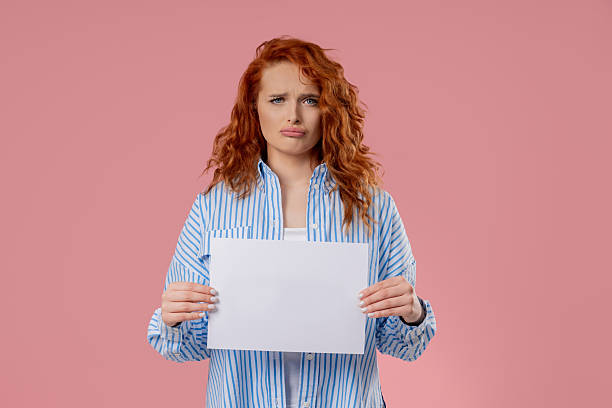 istock Young Sad Woman Holding Blank Billboard In Hands On Pink. Copy space, Mockup 2232767519