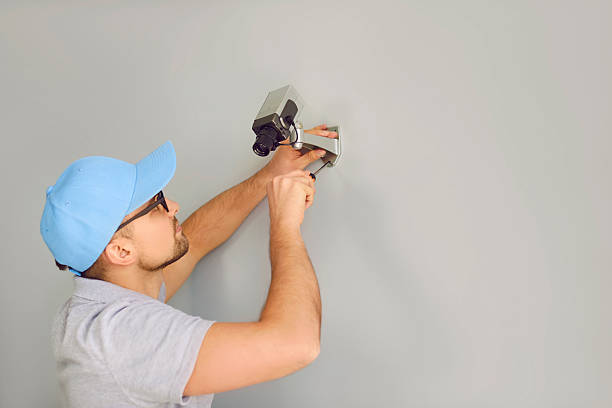 istock Company security specialist man mounts surveillance camera for CCTV system on wall inside building 2232770026