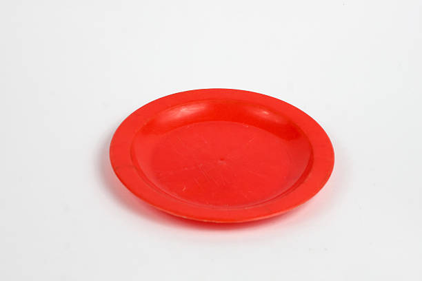 istock red plastic plate on a clean white background. The plate is circular and slightly concave, perfect for serving small items or use as a decorative piece. 2232770822