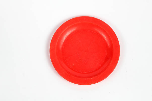 istock Red plastic plate on a clean white background. The plate is circular and slightly concave, perfect for serving small items or use as a decorative piece. 2232770861