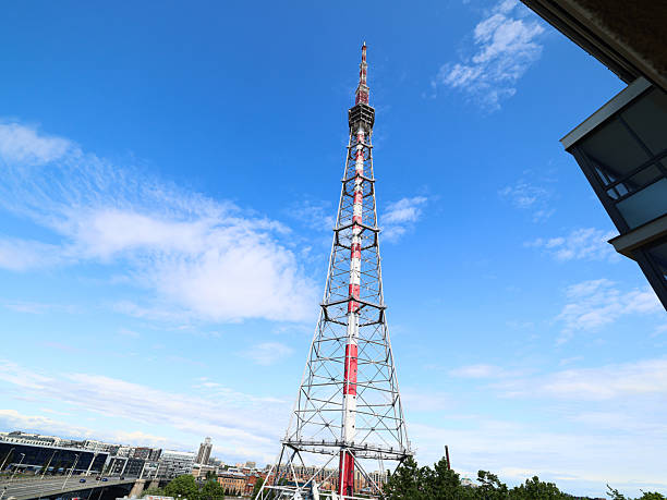 A tall telecommunication tower stands against a vibrant blue sky, showcasing technology and urban landscape.