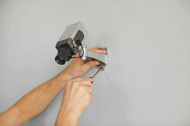 istock Hands master man mount camera for surveillance in anti-vandal metal case on wall inside building 2232773260