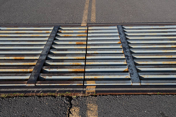 Close-up of rusty metal counterweights secured with a strap on an aluminum truss construction. Industrial detail with textures of corrosion, metal, and urban pavement. Concept of temporary structures, construction, and durability.