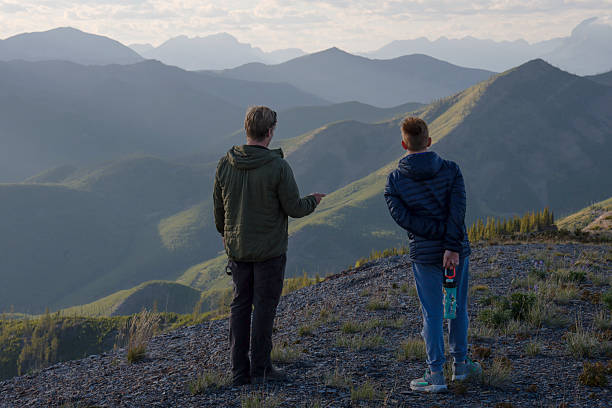 istock Young man and boy on mountain ridge at sunset 2232775614