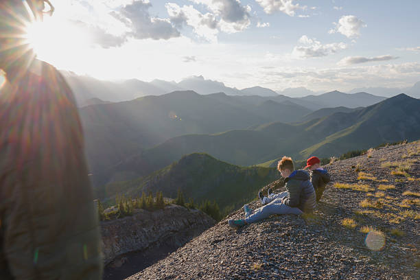 istock Boys watch sunset from mountain ridge at sunset 2232776812