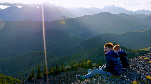istock Boys sit on edge of mountain top at sunset 2232777049