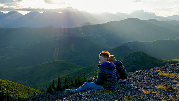 istock Boys sit on edge of mountain top at sunset 2232777050