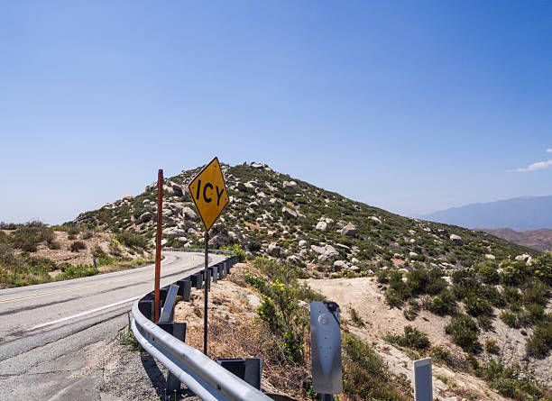 istock Scenic Mountain Road with an Icy Warning Sign Under Clear Blue Sky 2232780843