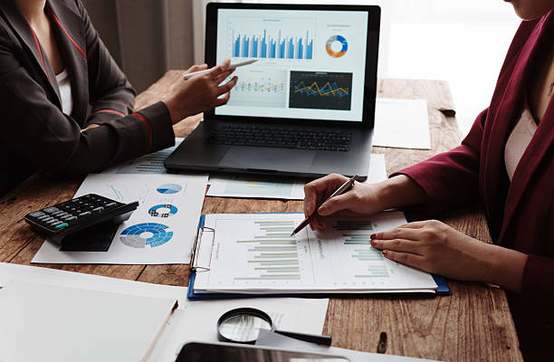 istock Two businesswomen are collaborating on a project, analyzing financial data displayed on a laptop and printed documents 2232781248