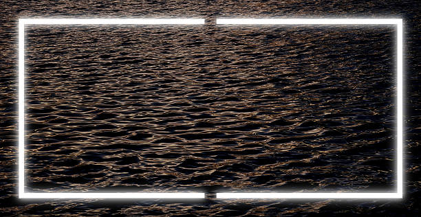 istock Dark choppy surface sea under subdued evening light. Bright glowing neon frame in soft white hue is centered over the water creating a strong contrast. Light frame reflects on waves 2232786283