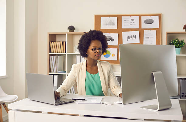 istock Female secretary works with electronic business documents simultaneously on a computer and a laptop. 2232786577