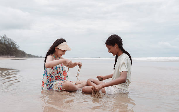 istock Asian and multicultural daughters playing with sand beach water. Childhood joy, creativity, and diversity in a happy and peaceful seaside moment. 2232788091