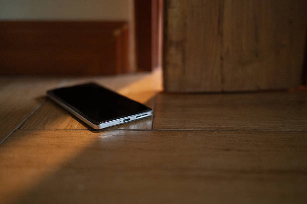 Beside the door, a smartphone lies forgotten on the ground. The quiet placement symbolizes the vulnerability of the devices we depend on most, lost in the blur of daily movement