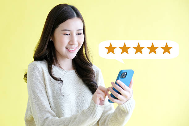 istock Young woman holding mobile phone , smiling while standing over isolated yellow background 2232796580