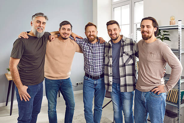 istock Smiling five male friends standing and hugging shoulders together 2232800454