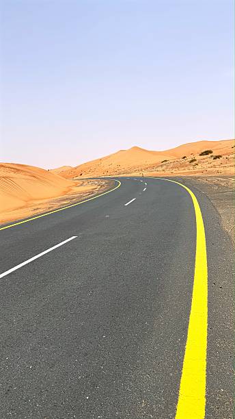 istock Empty asphalt road in desert stretching through breathtaking desert landscape, road surrounded by vast sand dunes under clear sunny sky, capturing endless golden horizons and open space. 2232800850