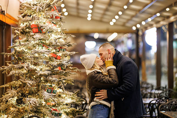 Lovely young couple hugging and kissing in Christmas decorated city at night