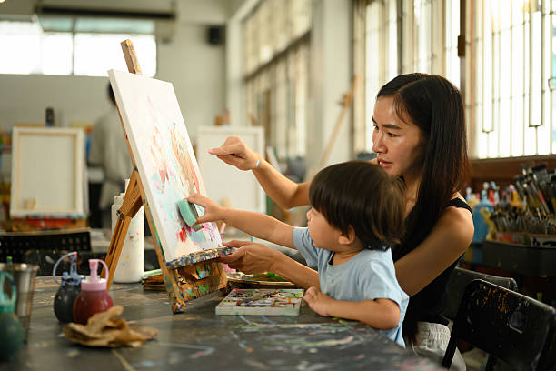 istock Parent and child sharing creative time together with paint, brushes, and an easel in a cozy classroom 2232805972