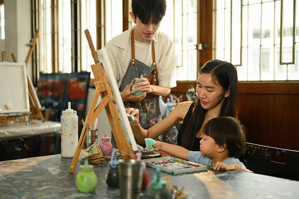 istock Teacher, mom, and young boy collaborate in a preschool art session, surrounded by paint tools and canvases 2232806014