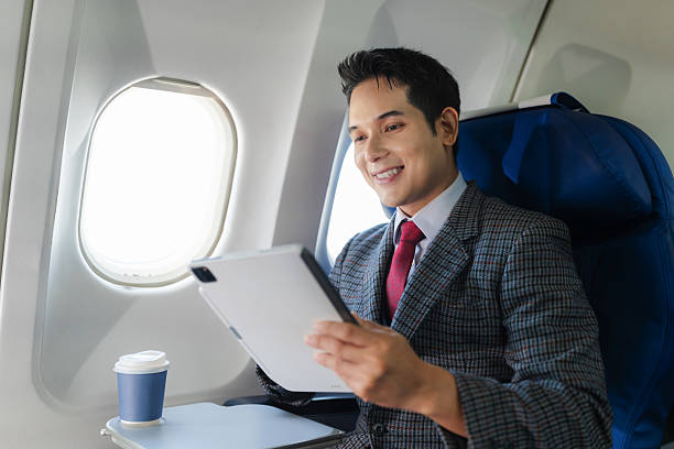 istock Traveling and technology. happy young businessman working on Tablet while sitting in airplane. 2232806640