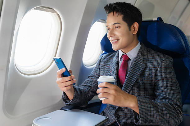 istock Smiling asian businessman enjoying comfortable flight while sitting in the airplane cabin, wifi internet on the plane. Passengers near the window. 2232806644