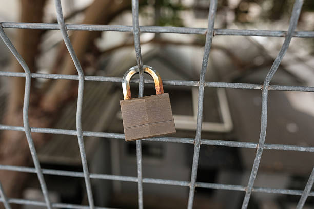 Close-up on an old padlock on a metal fence.