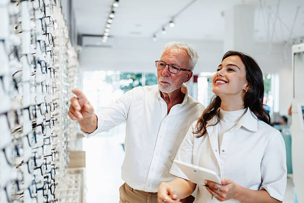 istock Senior man trying eyeglasses with optician in optical store 2232807042