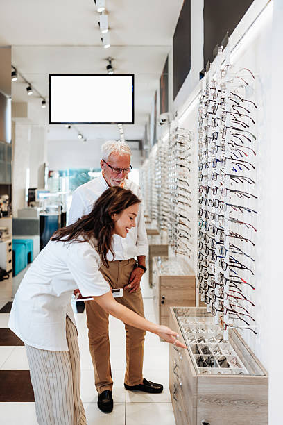 istock Senior man trying eyeglasses with optician in optical store 2232807066