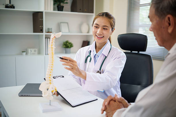 istock Orthopedic doctor educating aging patient about spinal health and posture using a human spine model. 2232809004