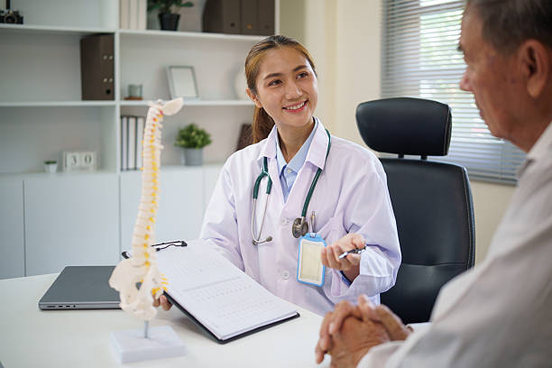 istock Smiling doctor discussing spinal health with elderly patient, using a spine model during a consultation. 2232809222